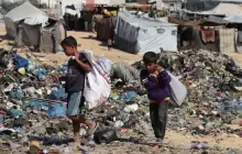 أطفال فلسطينيون يبحثون في القمامة بالقرب من مكب نفايات في قطاع غزة (رويترز)