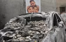 صورة أب وطفليه معلقة على جدار منزلهم الذي استهدفته الغارات الإسرائيلية وقتلتهم جميعا في قرية ساكساكية جنوب لبنان (أسوشيتد برس)