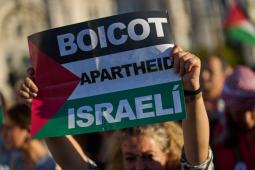 شابة ترفع علما فلسطينيا يتوسطه كلمات قاطعوا نظام الفصل العنصري الإسرائيلي