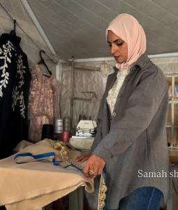 إسراء أبو القمصان داخل مشغلها لصناعة الملابس