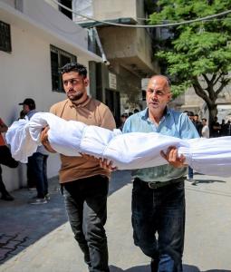 رجلان يحملان جثمان شهيد بغزة أمس