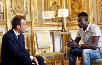 ماكرون أثناء استضافته المهاجر مامادو جاساما (رويترز)