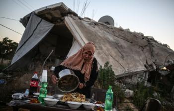 المواطنة شاهين تجهز مائدة الإفطار أمام منزلها المهدم (الأناضول)