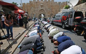 فلسطينيون يؤدون الصلاة أمام الأقصى احتجاجاً على البوابات الالكترونية (أ ف ب)