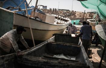 صيادون من غزة يُصلحون أحد المراكب (الأناضول)