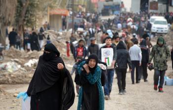 نازحون من الموصل يحملون مواداً إغاثية حصلوا عليها (أ ف ب)