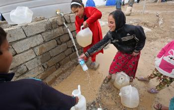 أطفال عراقيون نازحون من الموصل يقومون بتعبئة المياه في مخيم 