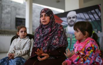 زوجة الشهيد البطش تتوسط ابنتيْه (الأناضول)