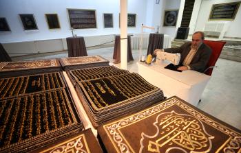 خطاط سوري تفنّن بحياكة القرآن على القماش (الأناضول)