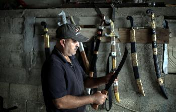 أبو وادي يستعرض بعضاً من السيوف التي صنعها (الأناضول)