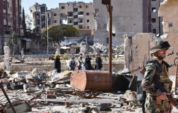 سوريون يتجولون في حي مساكن هنانو الذي سيطر عليه النظام السوري (أ ف ب)