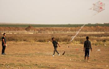 شبان فلسطينيون يطلقون طائرات ورقية قرب السياج الفاصل مع الاحتلال (أ ف ب)