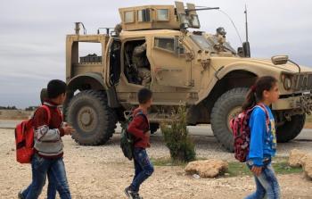 تلاميذ في الحسكة يمرون أمام آلية أمريكية (رويترز)