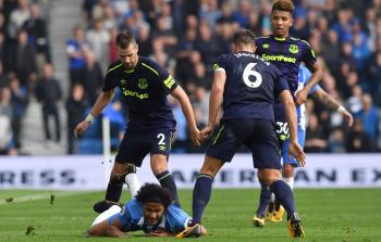 لاعبو إيفرتون يحاصرون لاعباً من برايتون خلال مباراتهما أمس (أ ف ب)