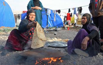 نازحات من الموصل يصنعن الخبز في مخيم للمشردين بالقرب من قرية ناهيا شمال مدينة القيارة بالموصل (أ ف ب)