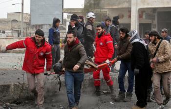 رجال إنقاذ سوريون ينتشلون جريحاً في إدلب (أ ف ب)