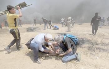 مواطنون يحاولون إسعاف أحد المصابين بعد استنشاقه الغاز المسيل للدموع في مسيرة العودة شرق خانيونس أمس (تصوير / رمضان الأغا)