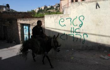 مستوطنون يخطون شعارات عنصرية بالقدس المحتلة (الأناضول)