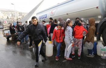 نازحون سوريون ينتظرون دورهم للحصول على الماء (أ ف ب)