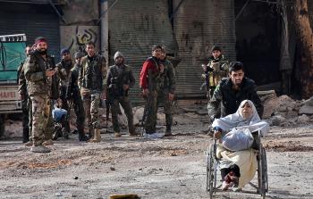 جندي من قوات النظام السوري يدفع امرأة جريحة في إطار إجلاء المدنيين من حلب (أ ف ب)