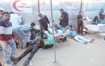 مسعفون وشبان يقدمون الإسعافات والعلاجات للجرحى خلال مسيرة العودة على حدود القطاع (تصوير / ياسر فتحي)