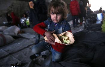 طفلة سورية من حلب تحمل رغيف خبز  (أف ب)
