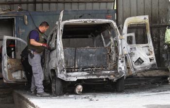 أفراد من شرطة الاحتلال يتفقدون السيارة التي أحرقها مستوطنون (الأناضول)