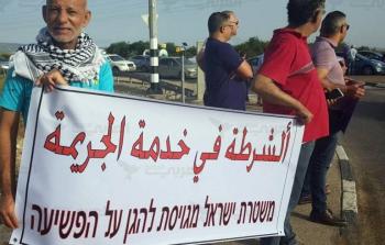 مواطنون في الداخل المحتل يرفعون لافتة تشير لشراكة شرطة الاحتلال في جرائم القتل (أرشيف)