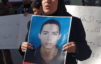 والدة الشاب نزال تحمل صورة ابنها في اعتصام طالبت خلاله بالافراج عنه