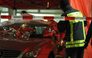 عنصر أمني يقف إلى جانب سيارة استخدمها الجناة في عملية إطلاق النار (الفرنسية)