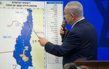 رئيس حكومة الاحتلال نتنياهو وأمامه خارطة تظهر مخططات الاستيلاء على المناطق الفلسطينية في منطقة الأغوار (أرشيف)