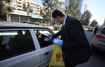 أحد موظفي صحيفة فلسطين يوزع الكمامات على المواطنين (تصوير: محمود أبو حصيرة)