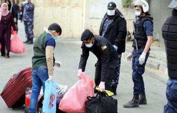 أحد أفراد الأجهزة الأمنية بغزة يحمل حقائب أحد الأسر التي كانت في الحجر الصحي بعد انتهاء فترة احتجازهم احترازيا