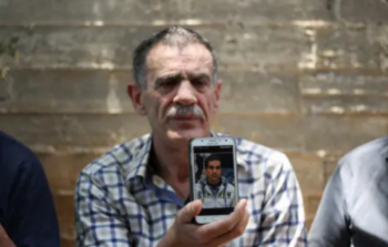 والد الشاب الشهيد إياد الحلاق يحمل هاتفا محمولا فيه صورة نجلة