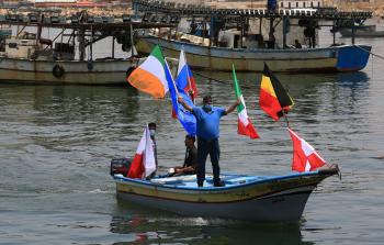 ناشط يرفع أعلاما على ظهر قارب في بحر غزة (تصوير محمود أبو حصيرة)