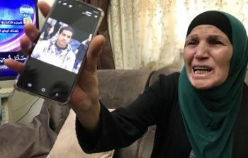 والدة الشاب الشهيد إياد الحلاق ترفع هاتفا محمولا فيه صورة نجلها الشاب الشهيد إياد الحلاق