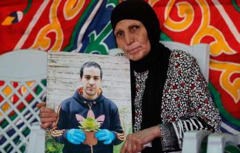 والدة الشهيد إياد الحلاق تحمل صورته