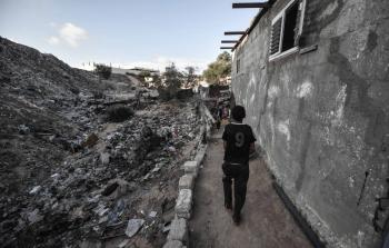 طفل يسير إلى جانب أكوام من القمامة في مخيم نهر البارد بخان يونس (أرشيف)