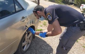 عنصر من شرطة الاحتلال إلى جانب إحدى السيارات