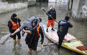 فرق الدفاع المدني تنقذ طفلا جراء الأمطار (تصوير: الفرنسية)