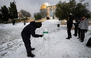 صورة لشاب يقف وهو يختتم تشكيل المجسم الثلجي لصاروخ أم 75 في ساحة الأقصى