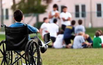 طفل من ذوي الهمم يشاهد أقرانه خلال استراحة قصيرة من لعب الكرة (أرشيف)