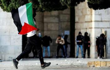 شاب يرفع علم فلسطين في مواجهات الأقصى صباح اليوم (رويترز)