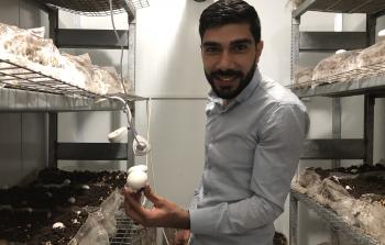 الشاب أحمد الهجين يقف وسط غرفة انتاج الفطر