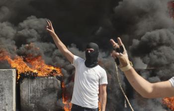 شبان يرفعون شارة النصر خلال مواجهات مع قوات الاحتلال في الخليل (الفرنسية)