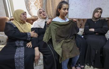 شقيقة الشهيد الشاب شحام تحمل في يديها ملابس شقيقها الغارقة بالدماء
