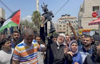 والدة الشهيد إبراهيم النابلسي تحمل سلاح نجلها الذي واجه فيه الاحتلال