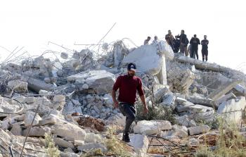 مواطنون يقفون على أطلال البناية المدمرة