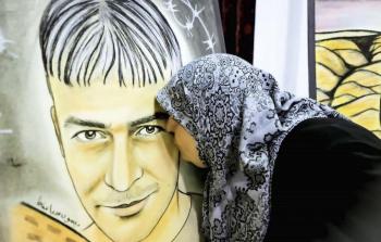 أم تقبل صورة ابنها الشهيد المحتجز جثمانه في مقابر الأرقام الإسرائيلية
