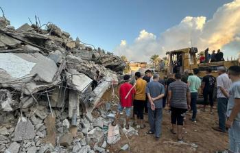 مواطنون وسط عدد من المنازل المدمرة وسط غزة